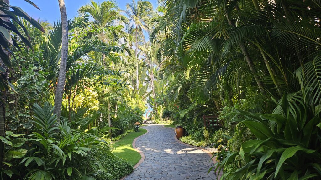 Scenic stone pathway through a lush green tropical garden inside Bamboo Village Resort.