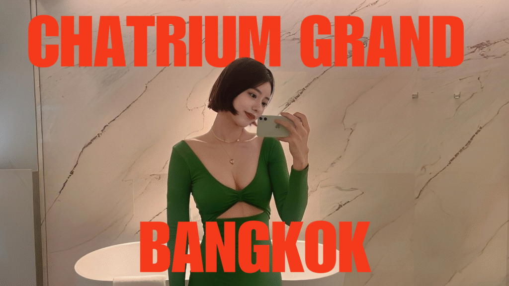 A woman in a green dress taking a mirror selfie in a luxury bathroom with a freestanding tub and marble walls.