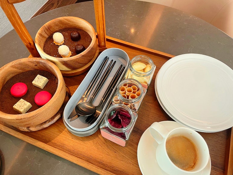 A cozy in-room setup at Chatrium Grand Bangkok with coffee, snacks, and a view of the bedroom and marble bathroom.