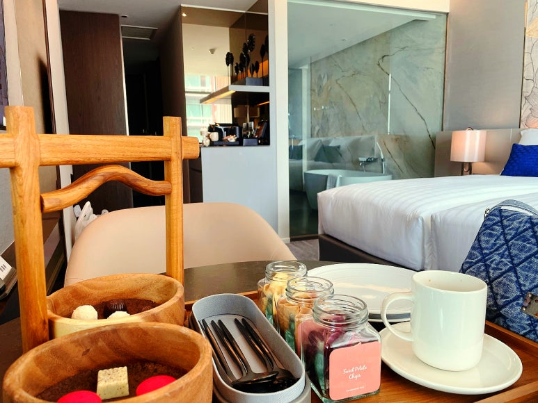 A tray of complimentary minibar snacks and espresso on a table at Chatrium Grand Bangkok.
