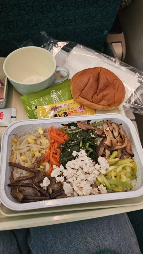 Vietnam Airlines in-flight bibimbap meal with assorted vegetables, seasoned tofu, and rice served with gochujang and sesame oil.
