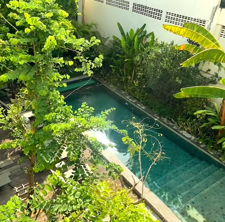 Peaceful outdoor swimming pool surrounded by tropical plants at Villa Prasumen Bangkok