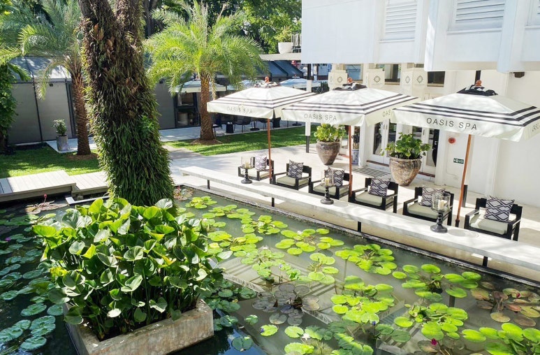 "Oasis Spa Sukhumvit 31's tranquil lily pond and outdoor seating area under parasols"